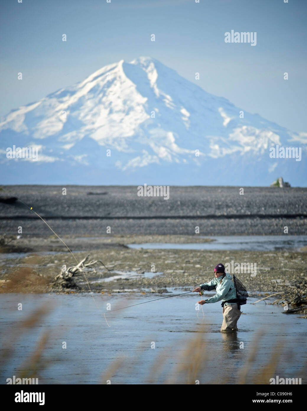 Mujer fly fishing Steelhead silvestres en Deep Creek con Mt. Reducto en el fondo, la Península Kenai, Southcentral Alaska Foto de stock