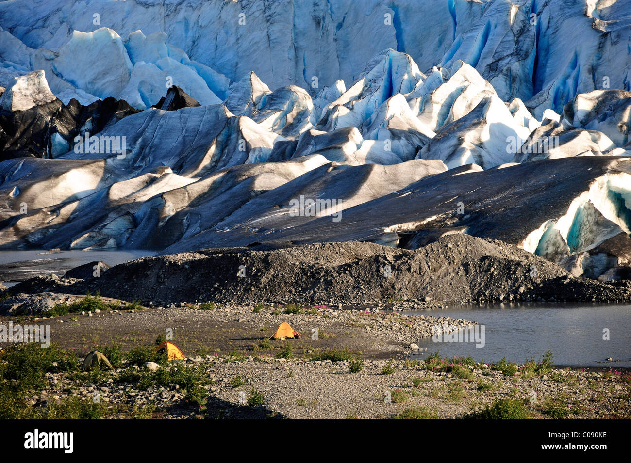 Tiendas levantadas a lo largo de la playa de grava en la parte frontal del Glaciar Spencer, el Bosque Nacional de Chugach, Southcentral Alaska, Verano Foto de stock