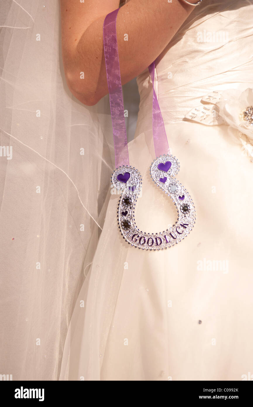 Una novia en un vestido de novia con un tradicional amuleto de buena suerte herradura Foto de stock