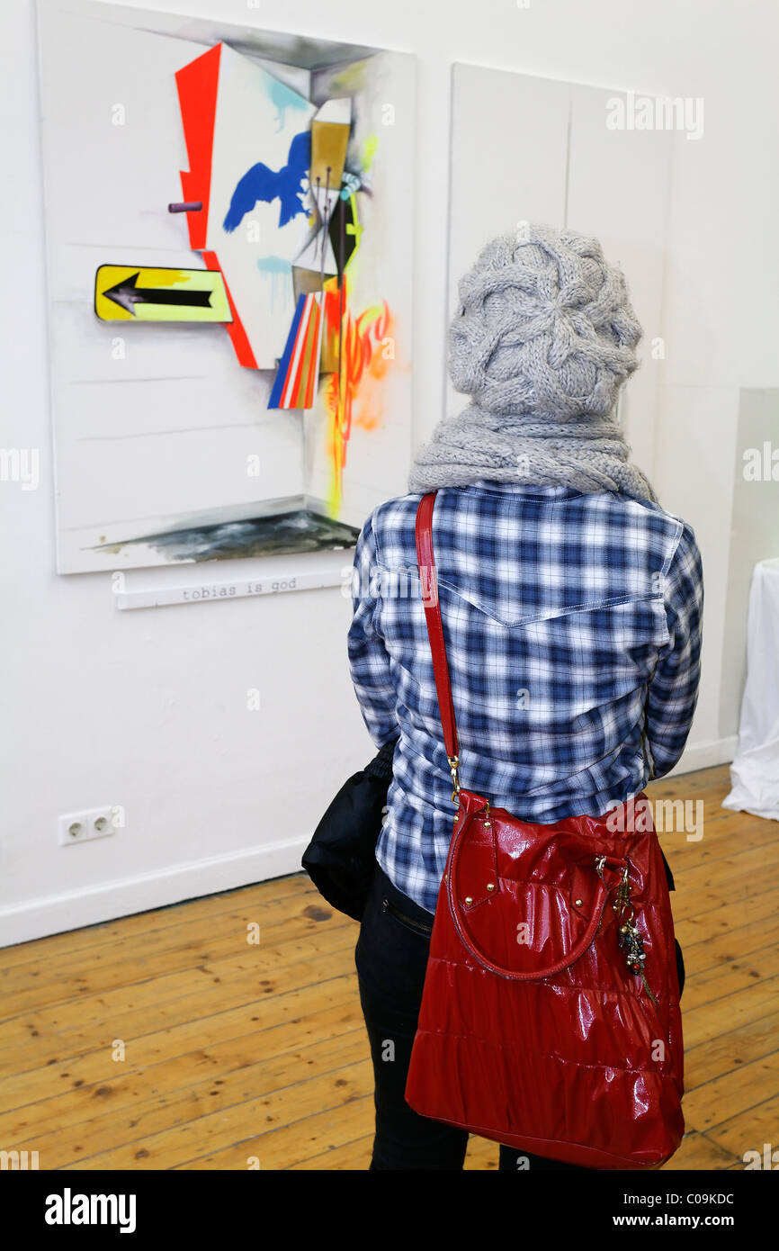 Mujer joven con gorro de lana mirando la pintura abstracta de un estudiante de arte, tour Kunstakademie Art Academy en Duesseldorf Foto de stock