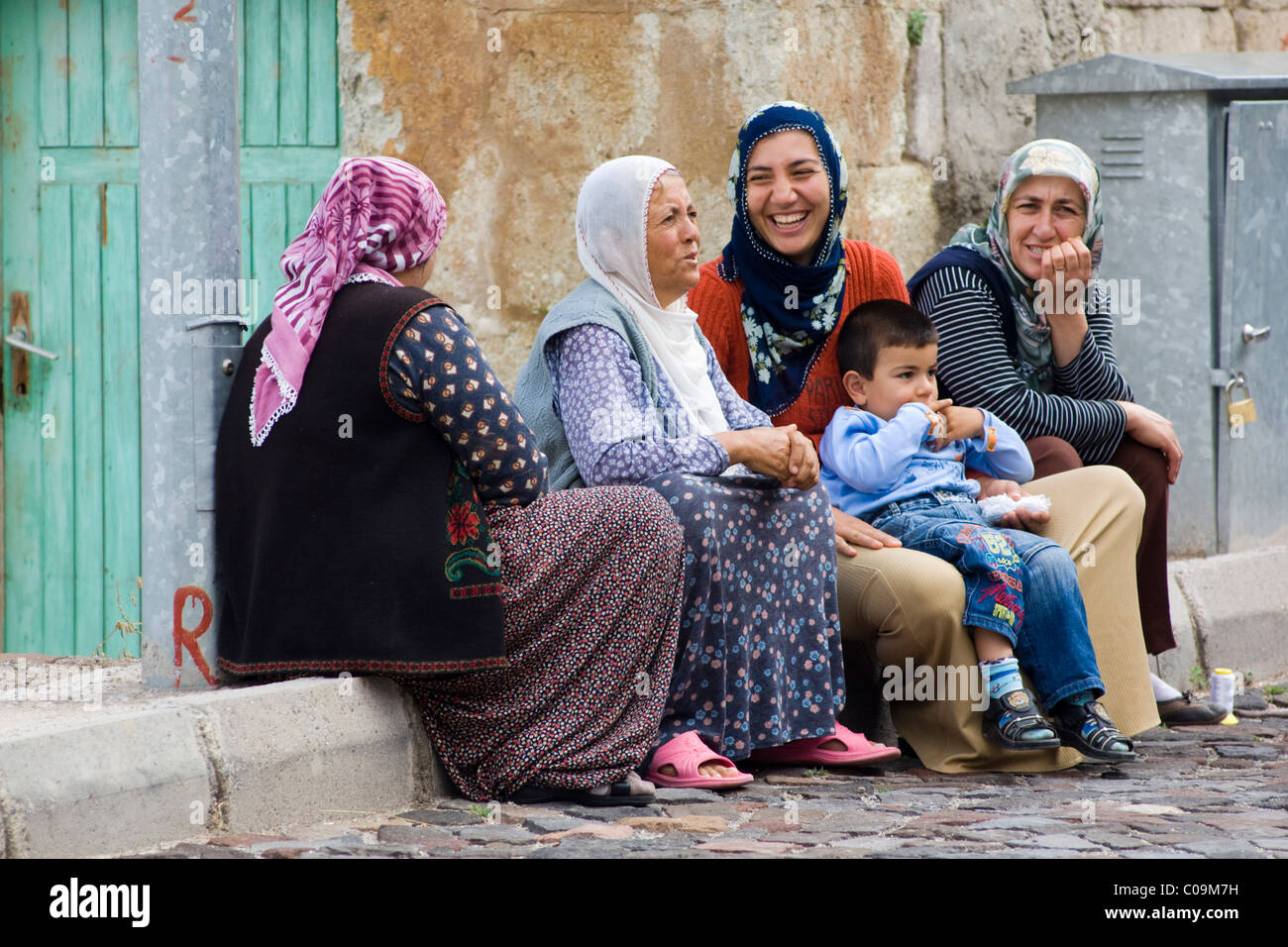 Las mujeres turcas y niños sentados en la carretera hablando, Urchisar, en Capadocia, en Anatolia, Turquía, Asia Foto de stock