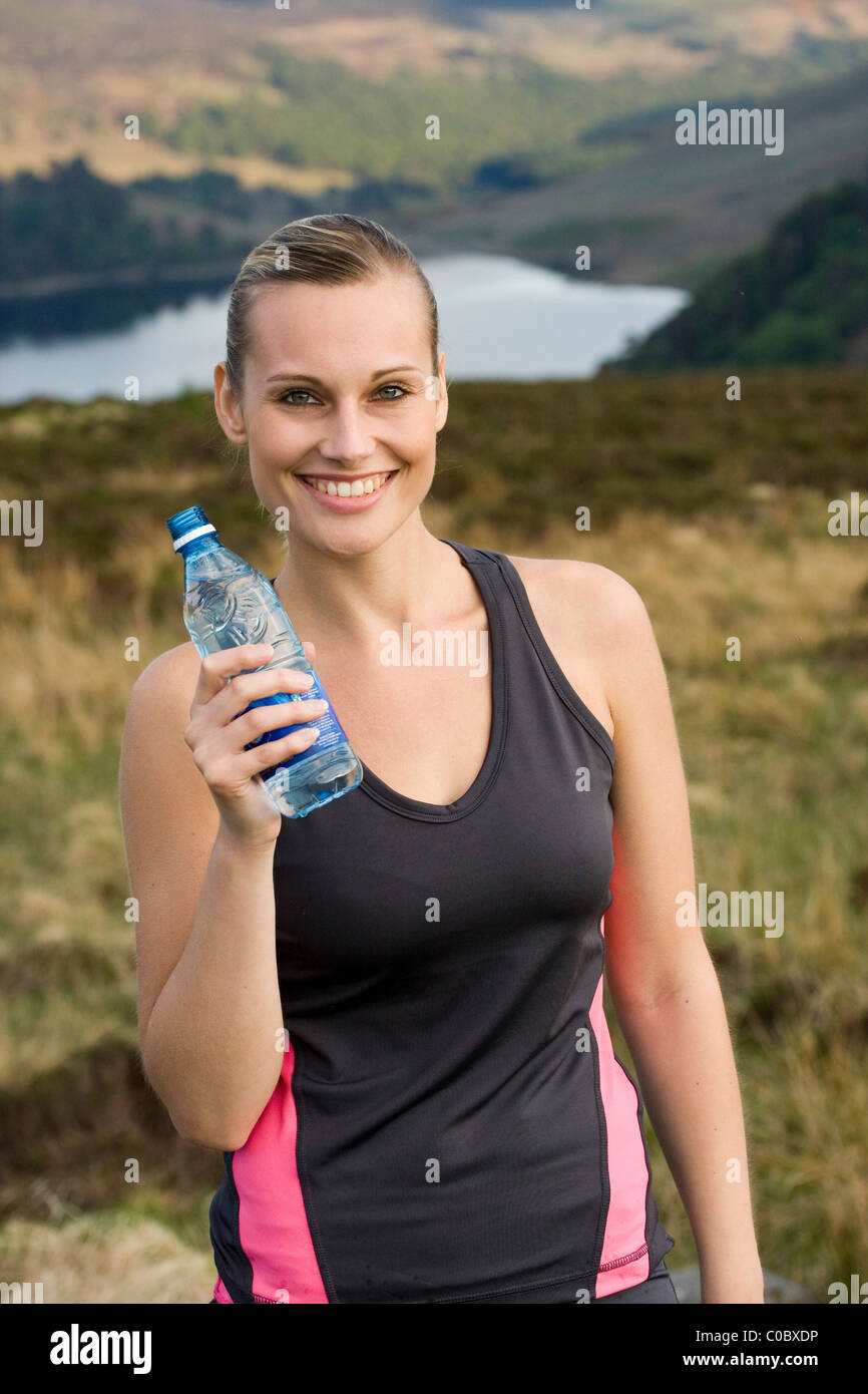 Hermosa niña caucásica deportivo sosteniendo una botella de agua después del ejercicio Foto de stock