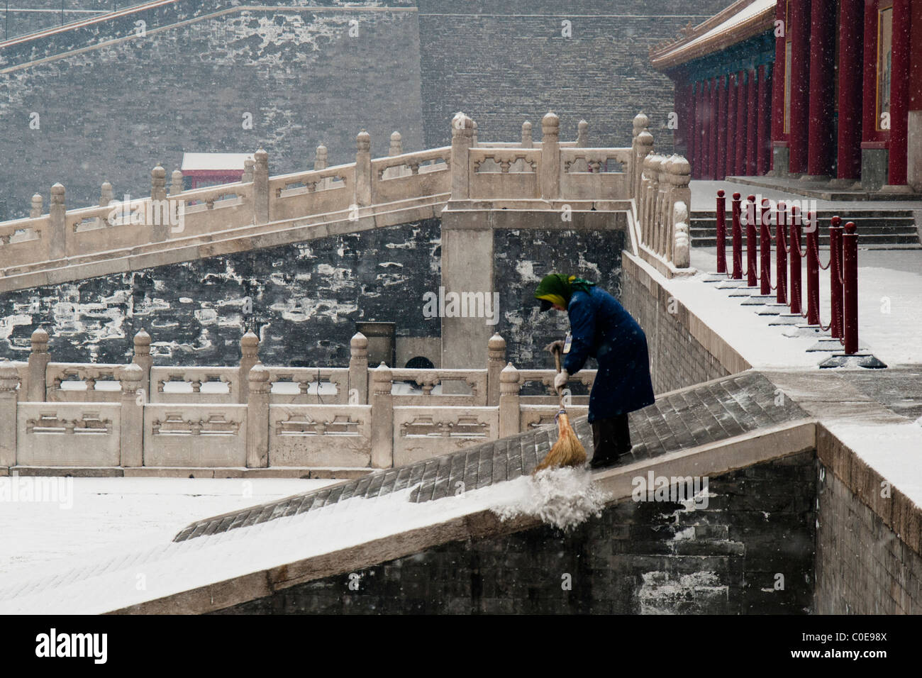 Attendant barrer la nieve de los escalones de la entrada de la Suprema Armonía de la Ciudad Prohibida de Beijing. Foto de stock