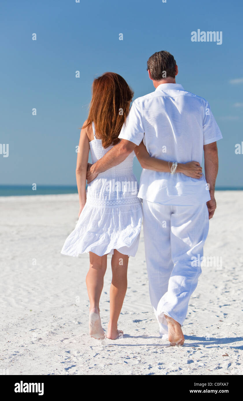 Vista trasera del hombre y mujer pareja romántica ropa blanca caminando en una desierta con brillante cielo azul claro Fotografía de stock - Alamy
