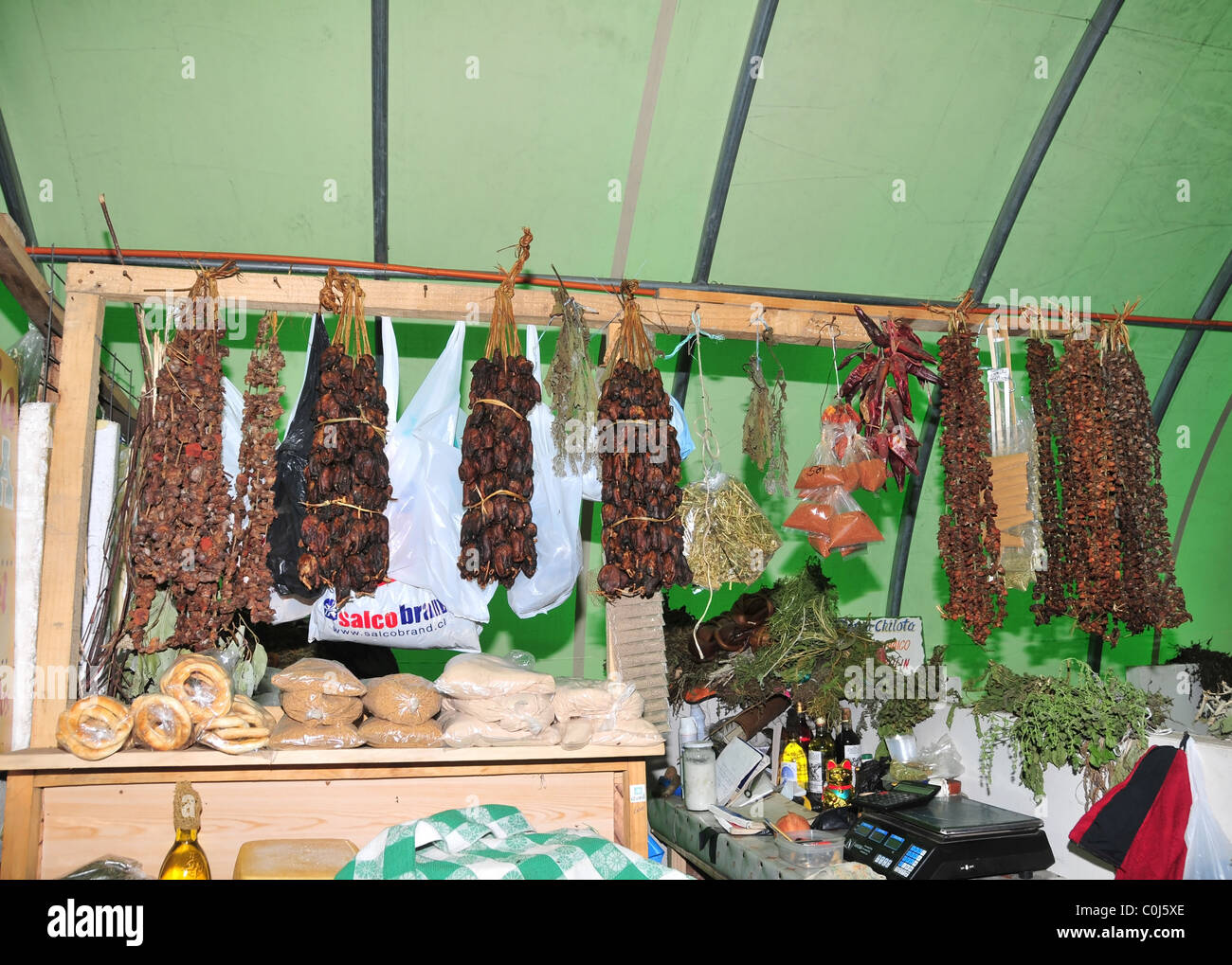 Paquetes de ahumados, mejillones y algas colgando de la parte delantera de un puesto en el mercado interior, Feria Municipal, Ancud, Chiloé, Chile Foto de stock