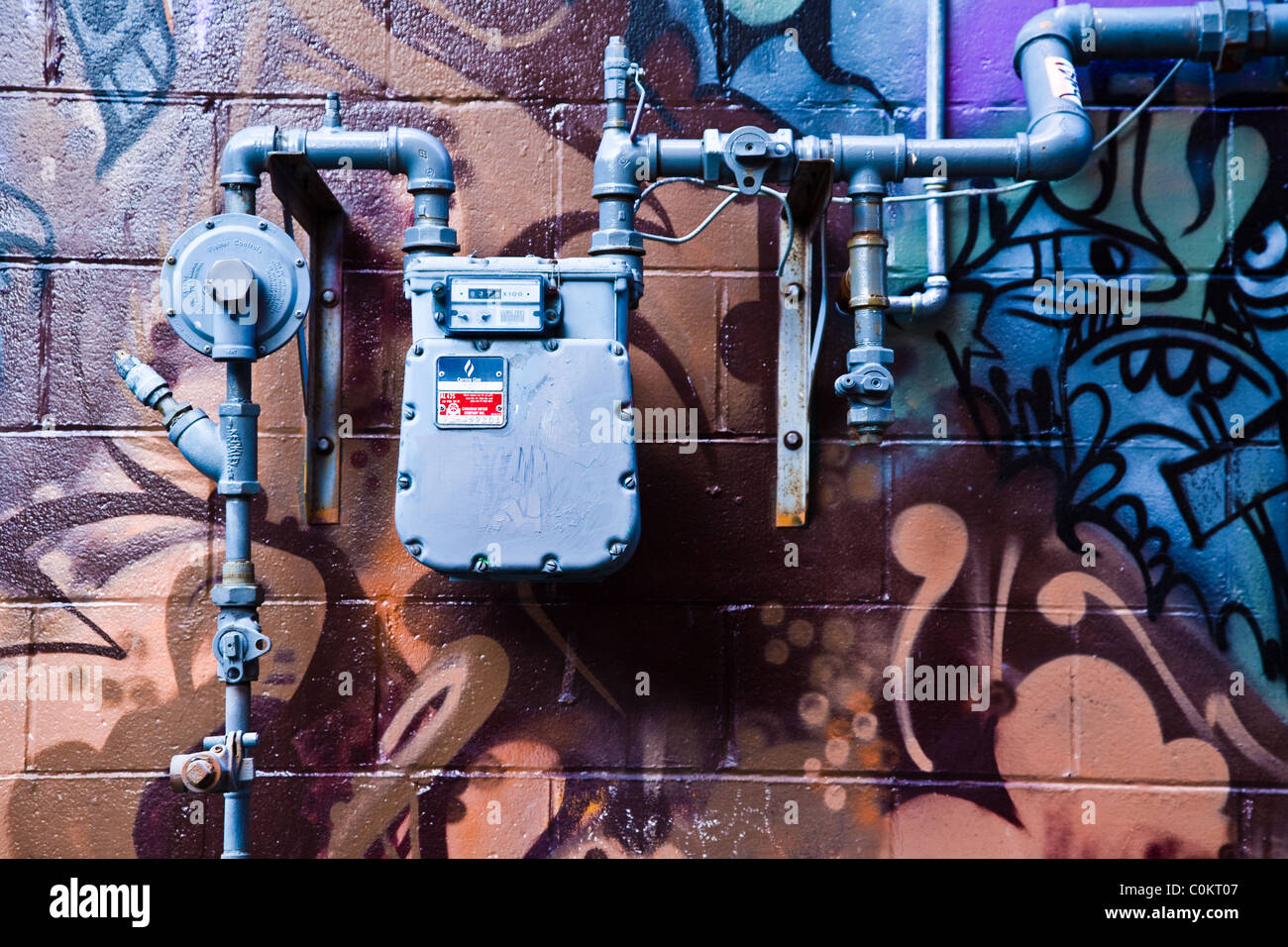 Un contador de gas y tuberías contra una pared colorida Foto de stock