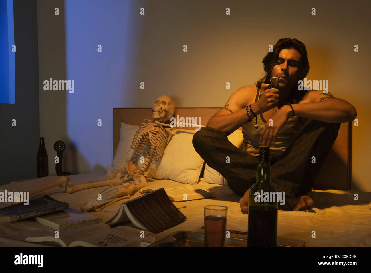 Hombre de fumar en la cama con el vino Foto de stock