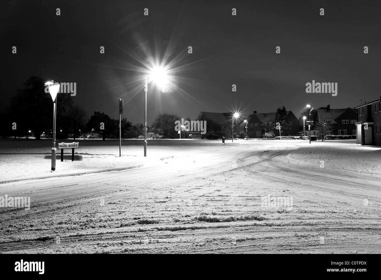 Un camino cubierto de nieve iluminado por las luces de la calle en la oscuridad. Foto de stock