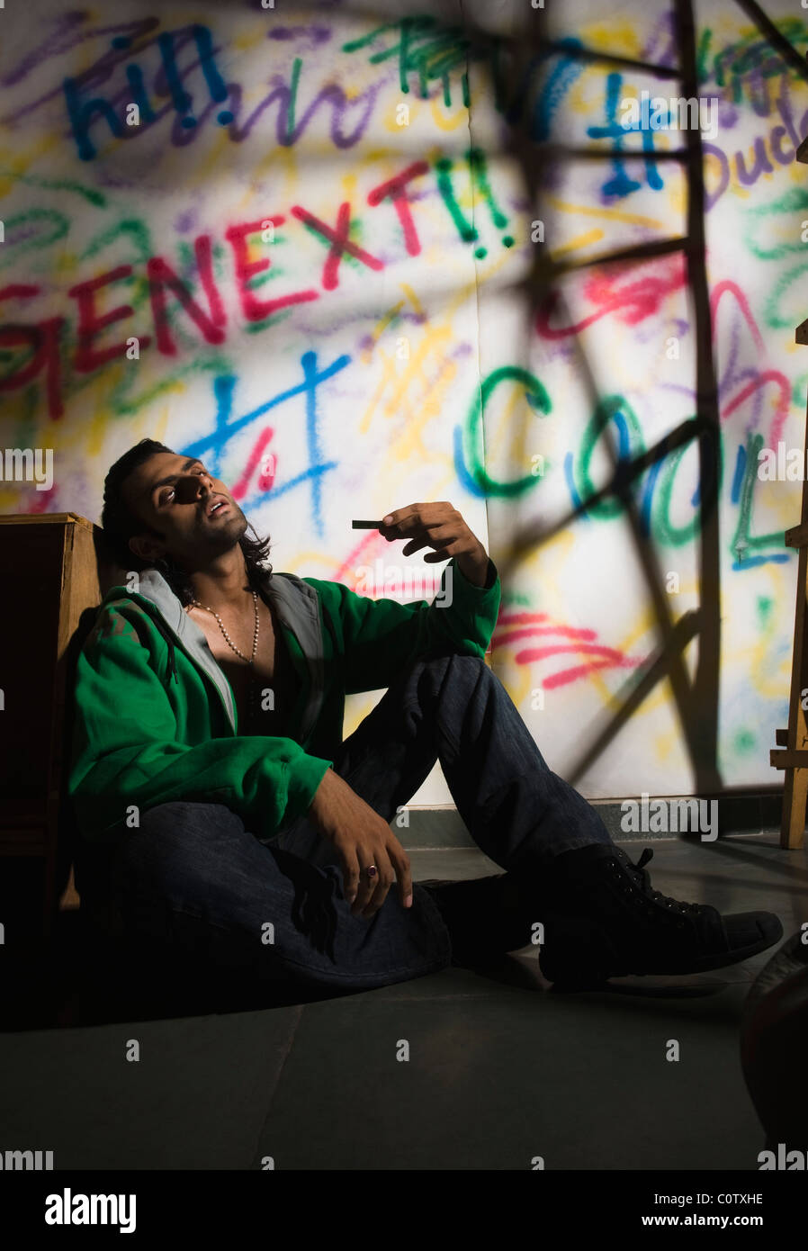 Drogadicto hombre sentado delante de una pared cubierta de graffiti Foto de stock
