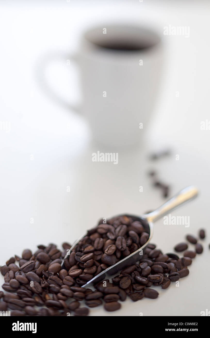 Boca de granos de café con taza de café en segundo plano. Foto de stock