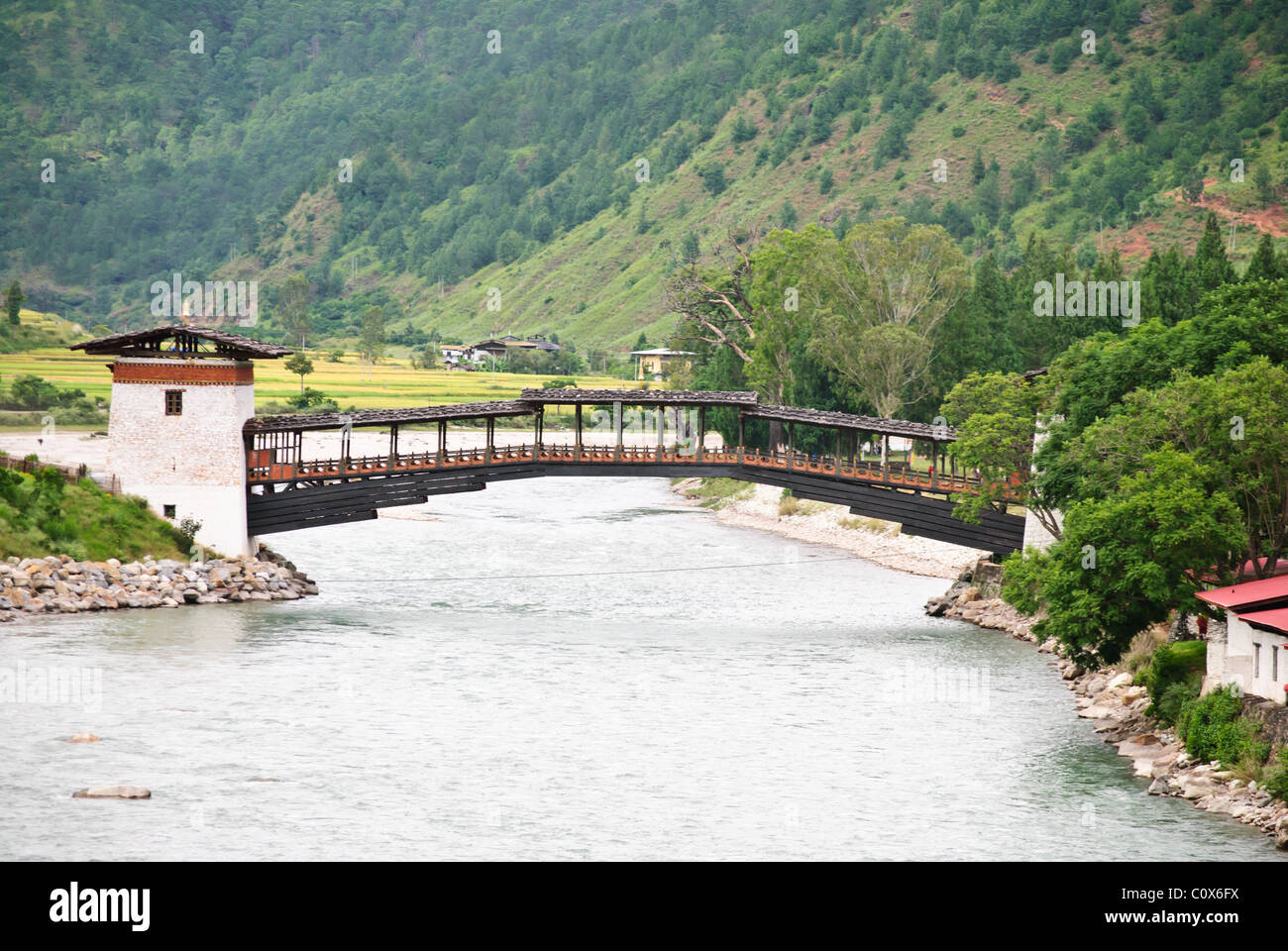 En voladizo tradicional puente que cruza el río hasta Punakha Dzong, Punakha, Bhután Foto de stock