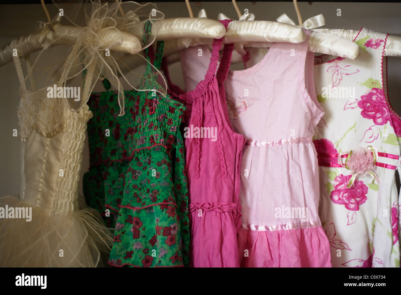 Los vestidos de niña en perchas acolchadas Foto de stock