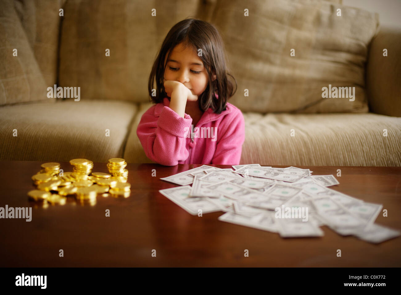 Decisión de inversión Girl hace entre chocolate monedas de oro y dólares de papel Foto de stock