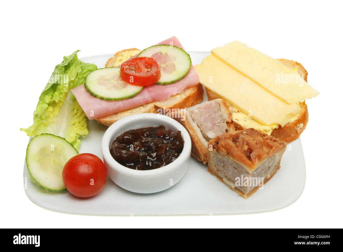 Plato de comida de cerdo, pasteles, pan, queso, jamón y ensalada aislado en blanco Foto de stock