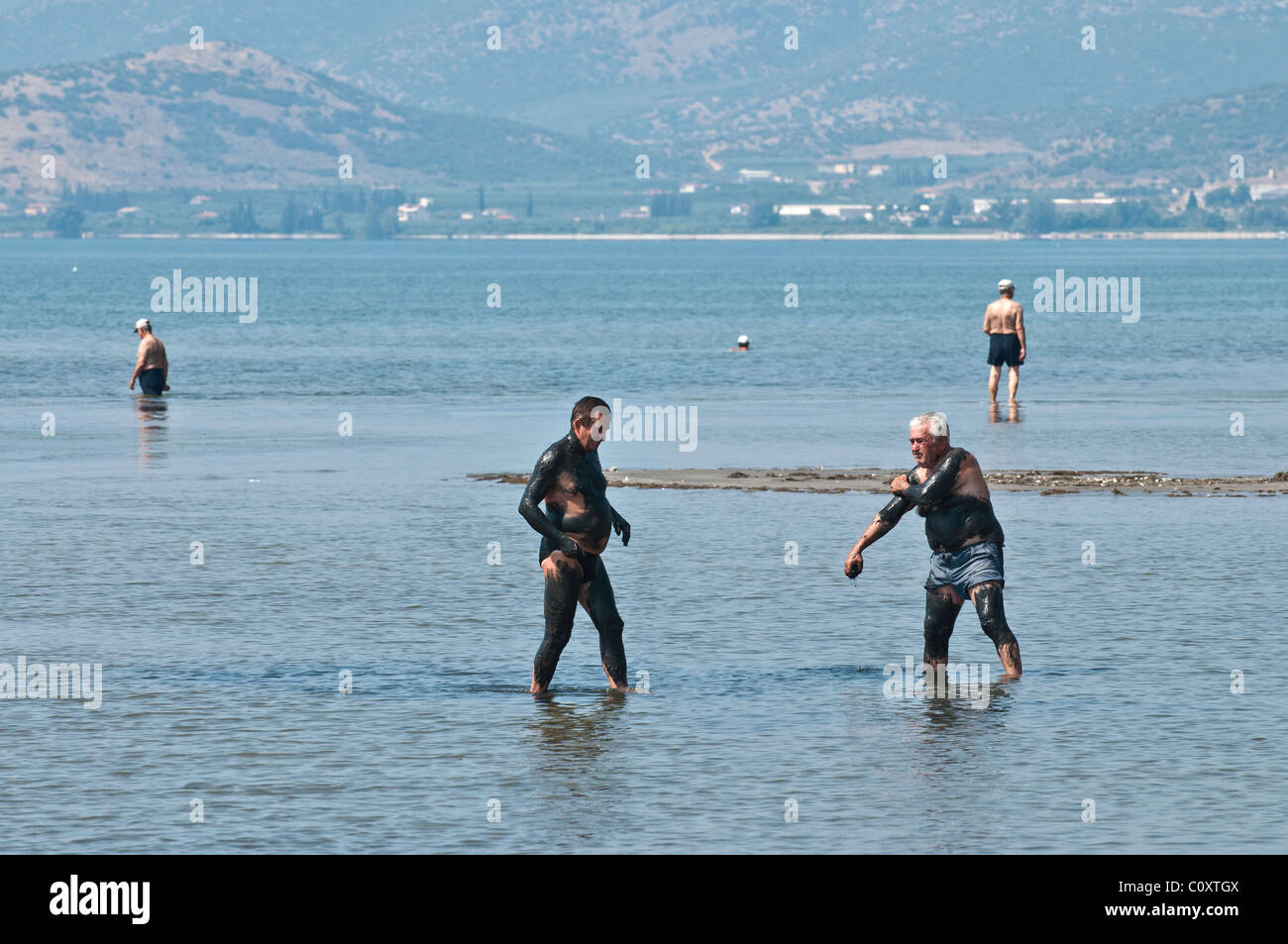 Los hombres griegos tomando un baño de barro terapéutico en la Bahía de Nafplio, Argolid, Peloponeso, Grecia Foto de stock