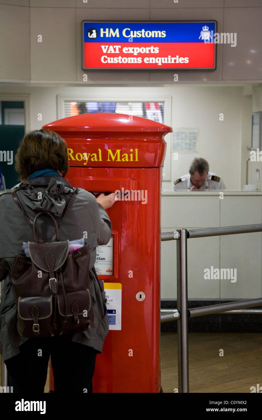Mujer puestos de pasajeros un sobre en un buzón de correo real al aeropuerto de Heathrow en Londres. UK Foto de stock