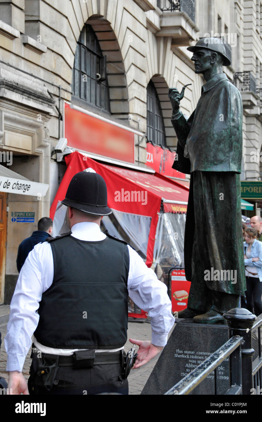 Beat policía patrullando zonas turísticas fuera de la estación de Baker Street con Sherlock Holmes escultura más allá de oscurecida firmar Foto de stock