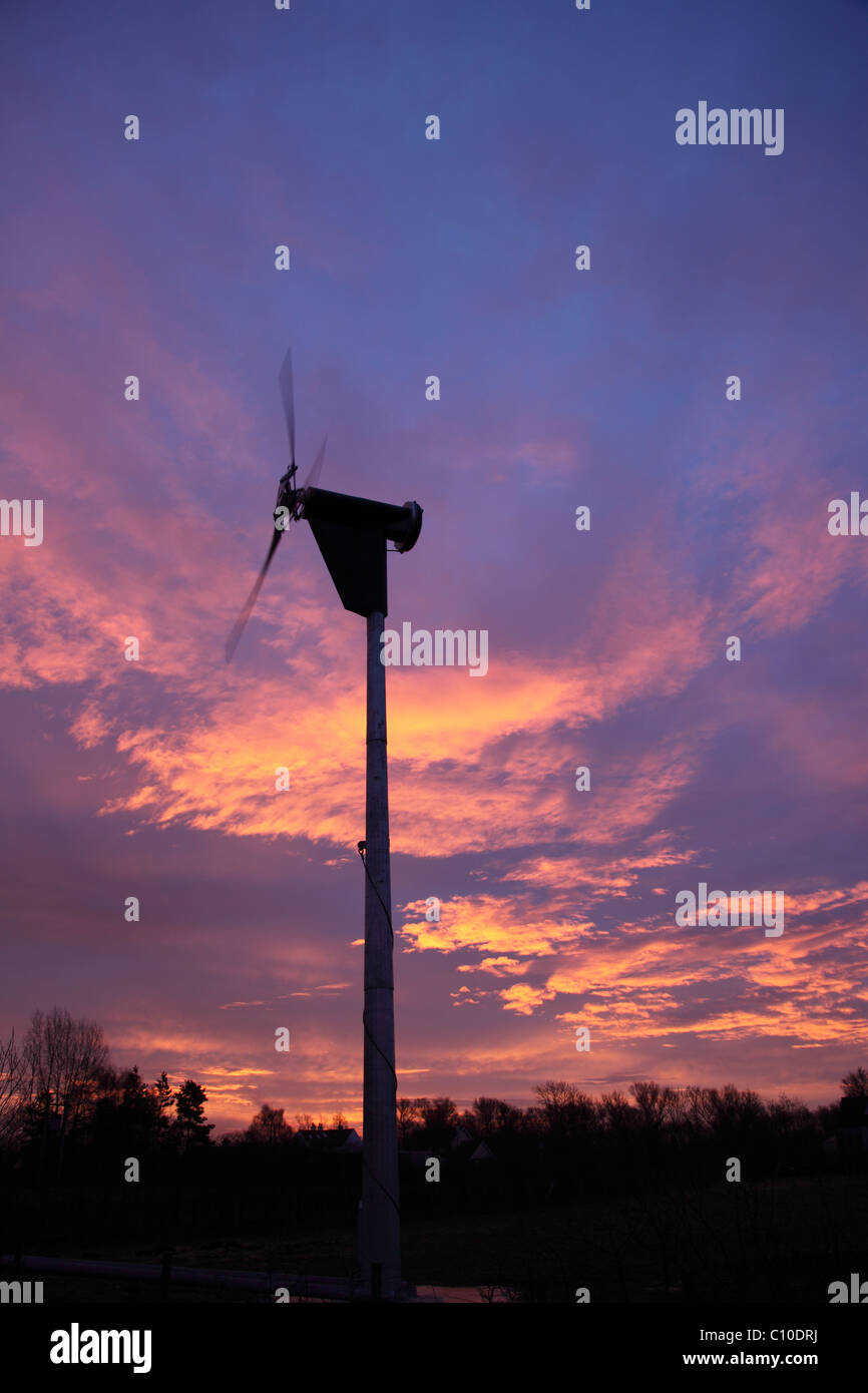Aerogenerador operacional contra el cielo del amanecer Foto de stock