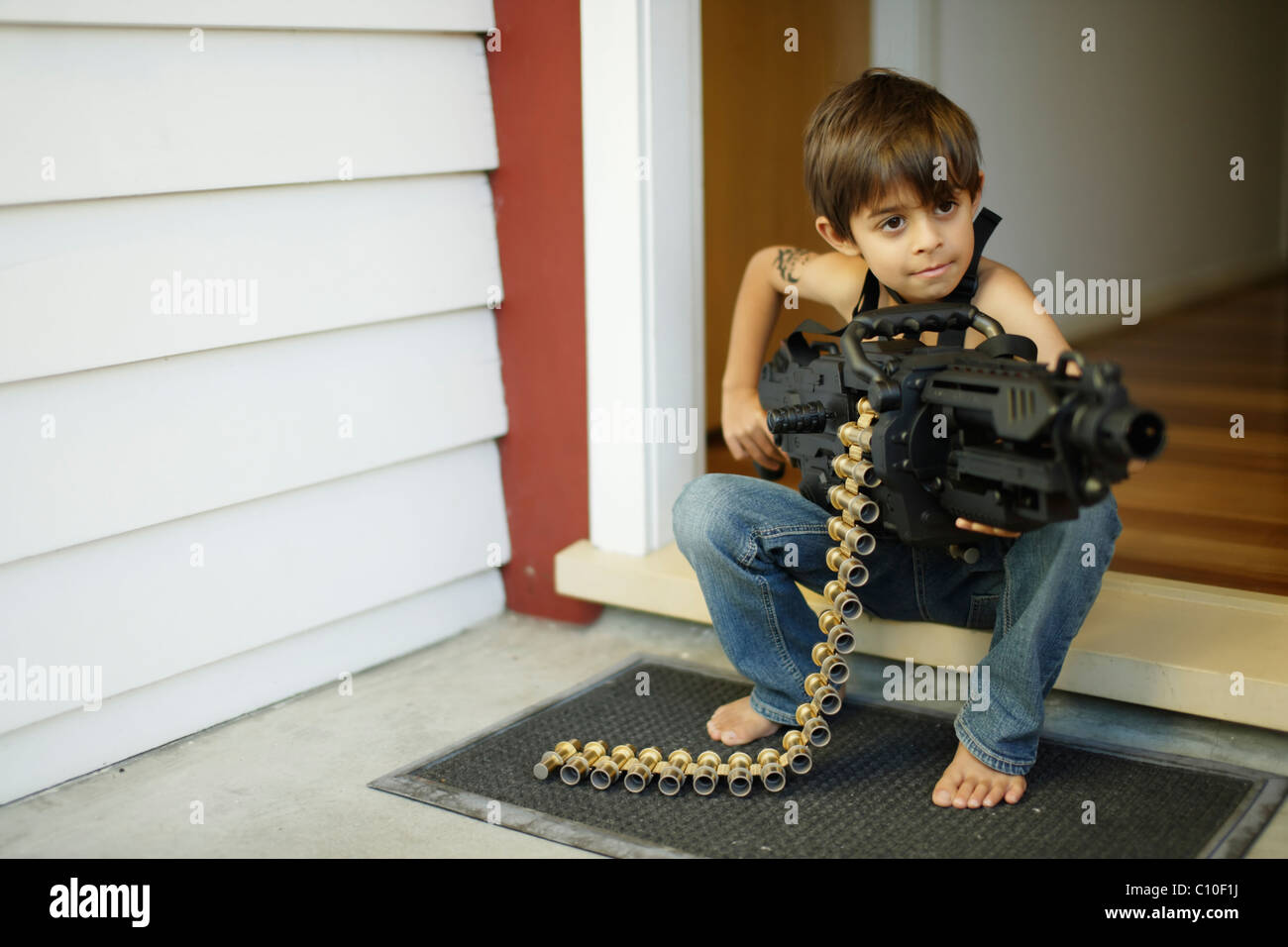 Los siete años de edad se encuentra en puerta la celebración de Toy Machine Gun Foto de stock