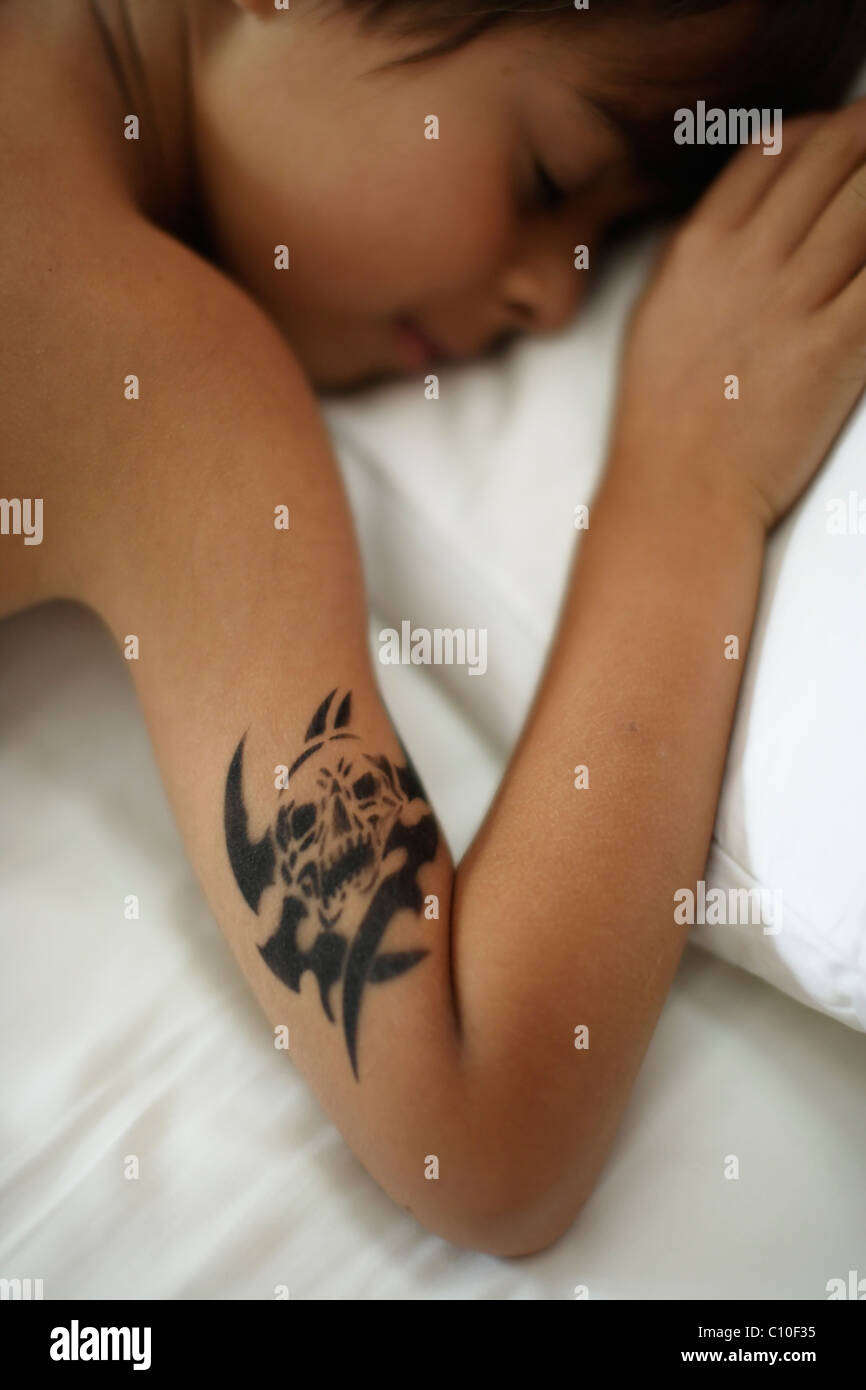 Los siete años de edad con contrato temporal tatuaje del cráneo durmiendo en cama Foto de stock