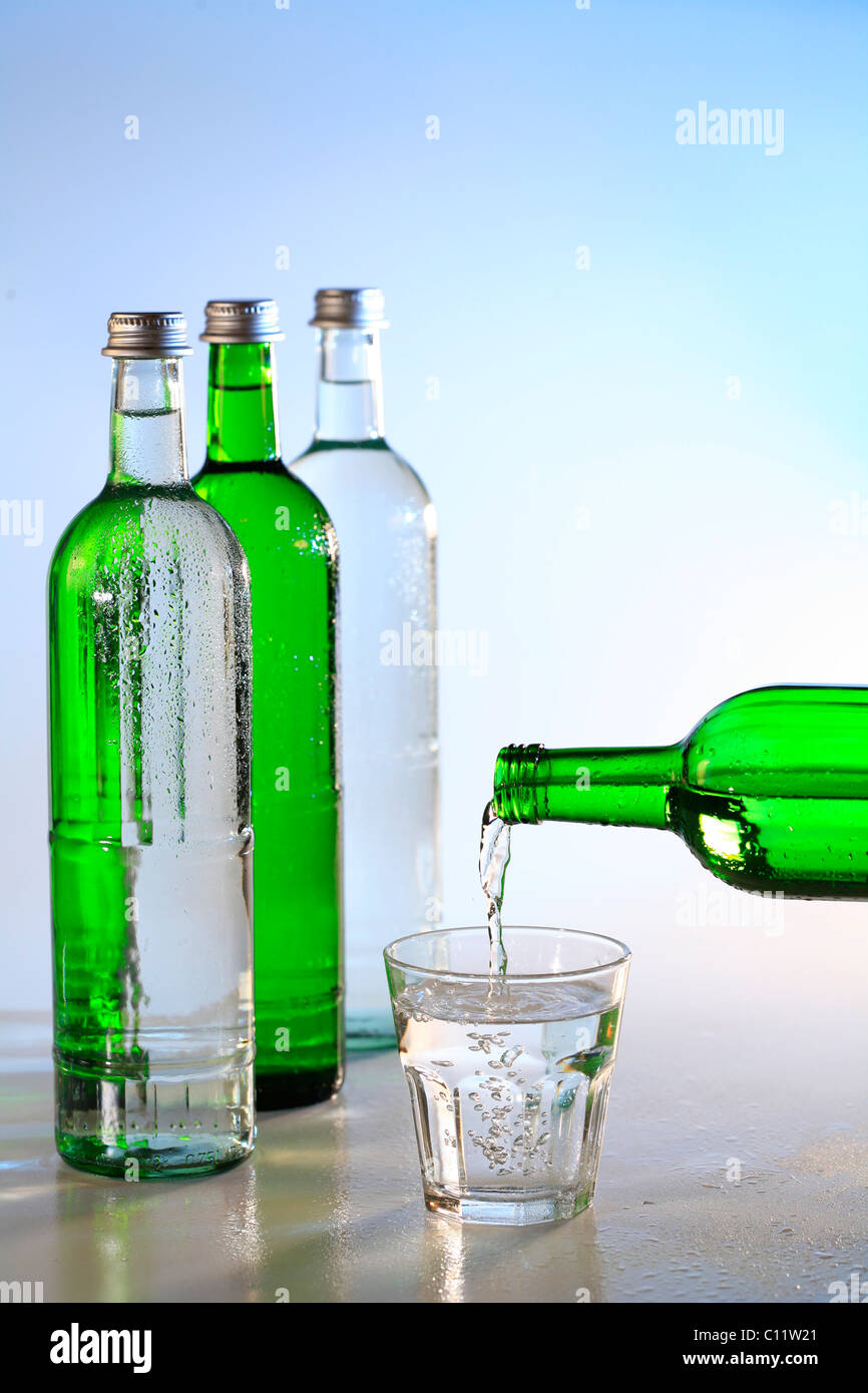 Botellas de agua mineral y un vaso de agua, agua potable Foto de stock