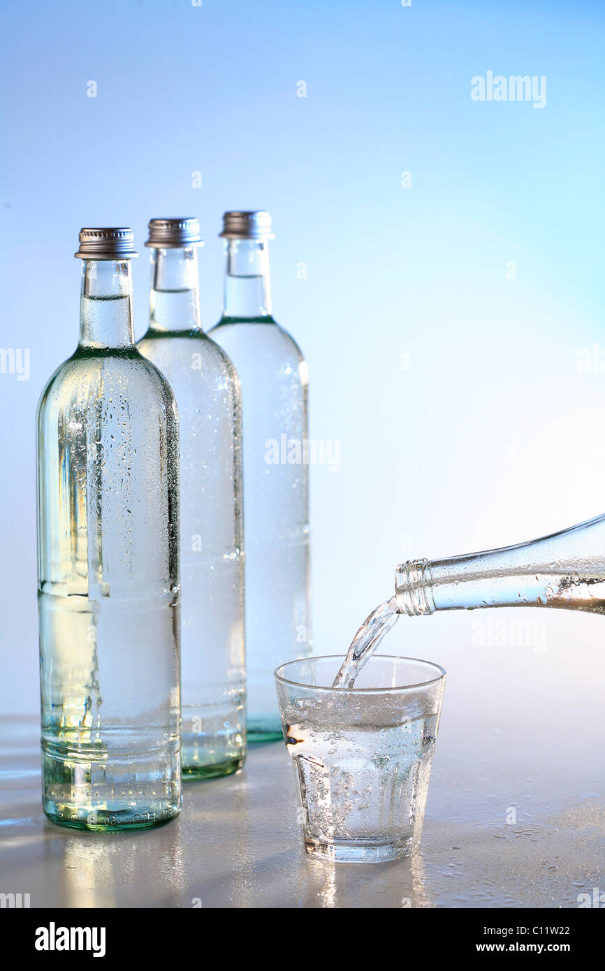 Botellas de agua mineral y un vaso de agua, agua potable Foto de stock