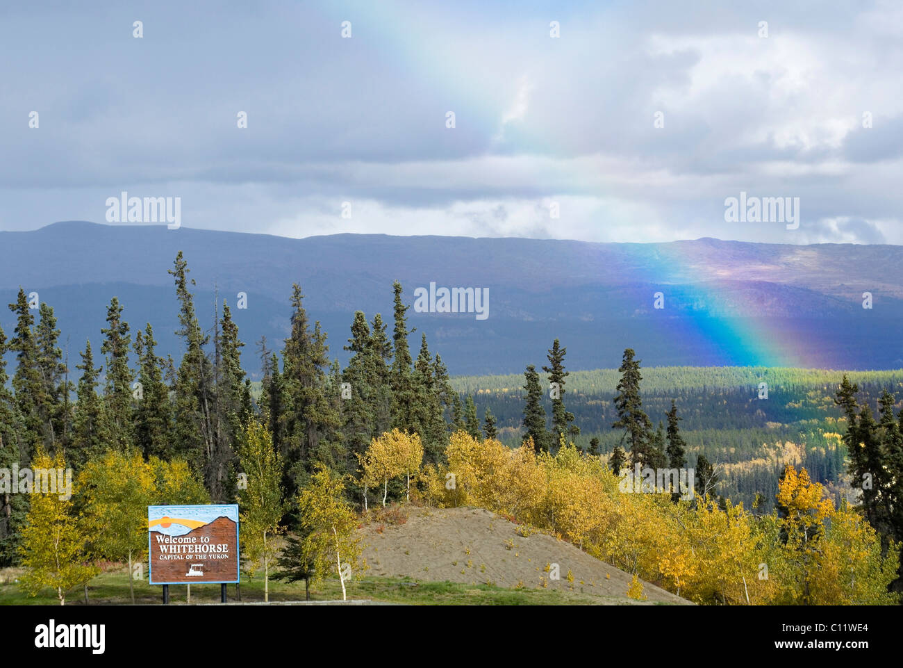 Rainbow, verano indio, árboles en colores de otoño, Whitehorse acogedor signo, Two Mile Hill, Whitehorse, capital del Territorio del Yukón Foto de stock