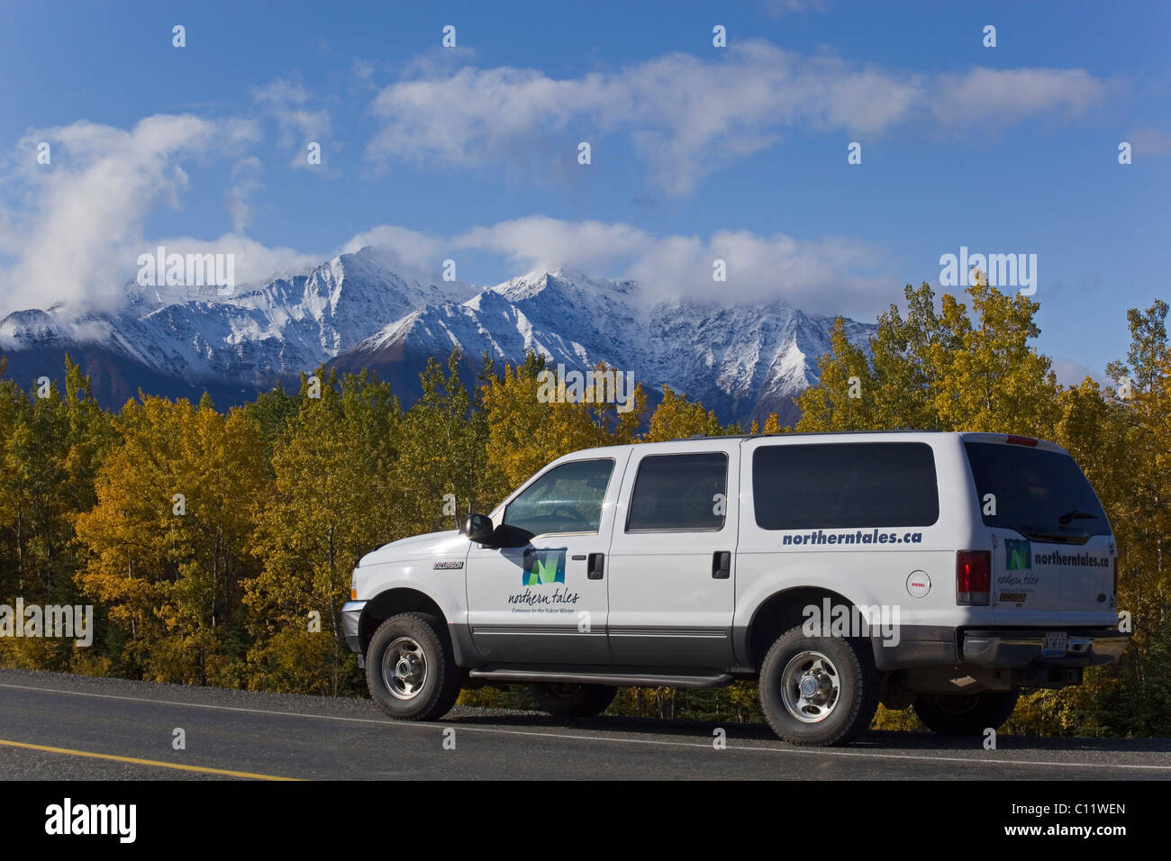 SUV conduciendo a lo largo de Alaska Highway, verano indio, árboles en colores de otoño, San Elías montañas detrás Foto de stock