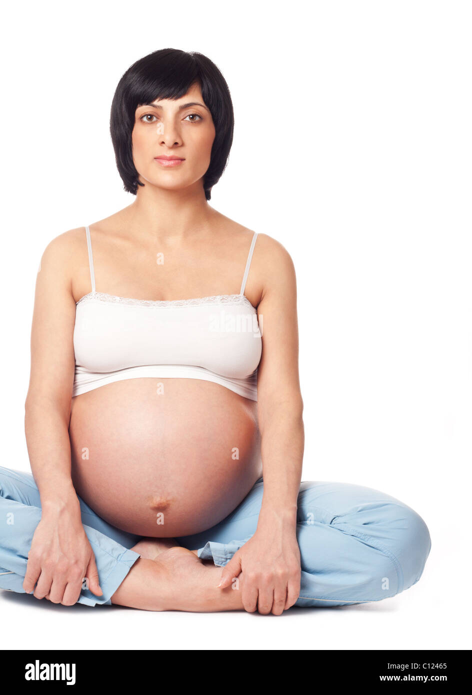 Mujer embarazada sentada aislado sobre fondo blanco. Foto de stock