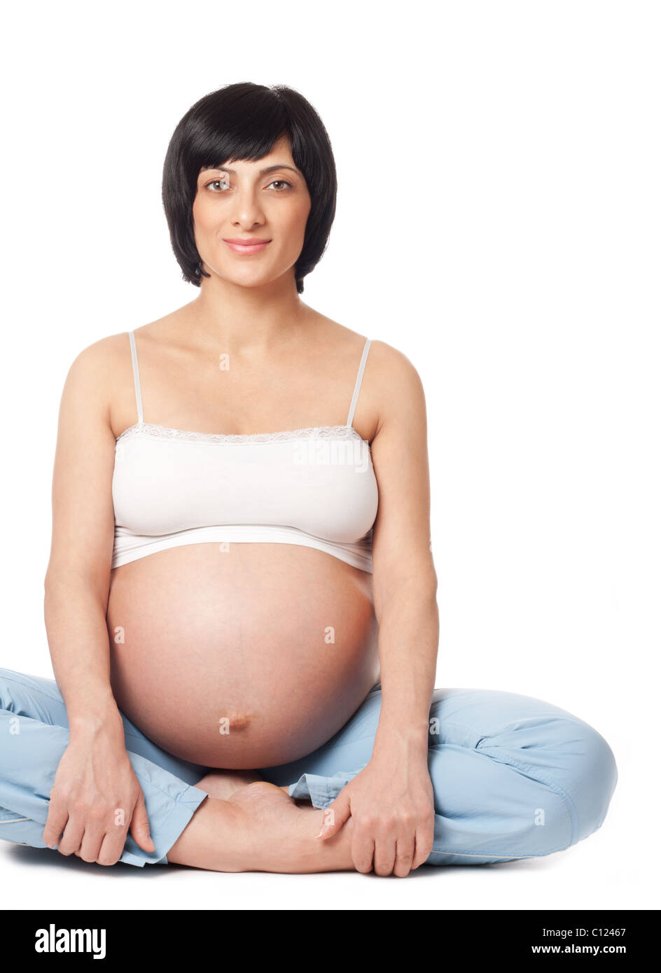 Sentado sonriente mujer embarazada aislado sobre fondo blanco. Foto de stock
