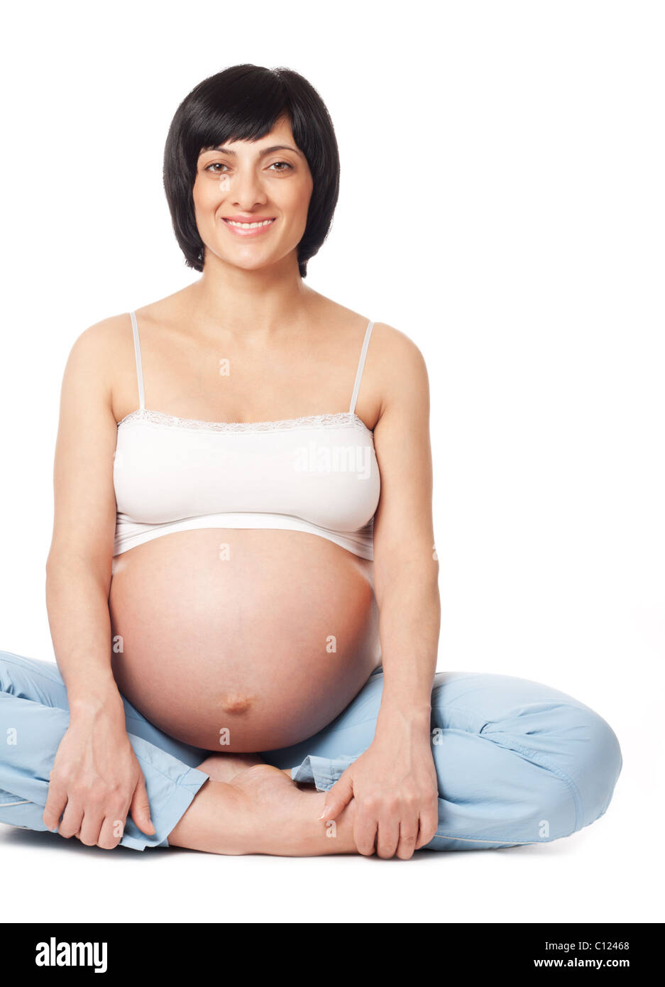 Sentado sonriente mujer embarazada aislado sobre fondo blanco. Foto de stock