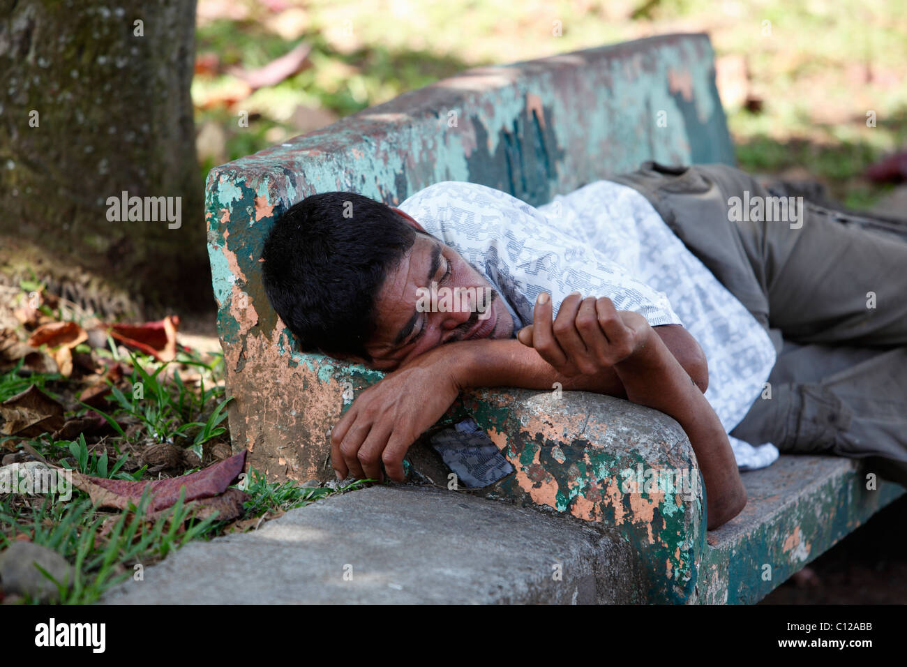 Un hombre Costarricense durmiendo en una banca del parque en Quepos, Costa Rica Foto de stock