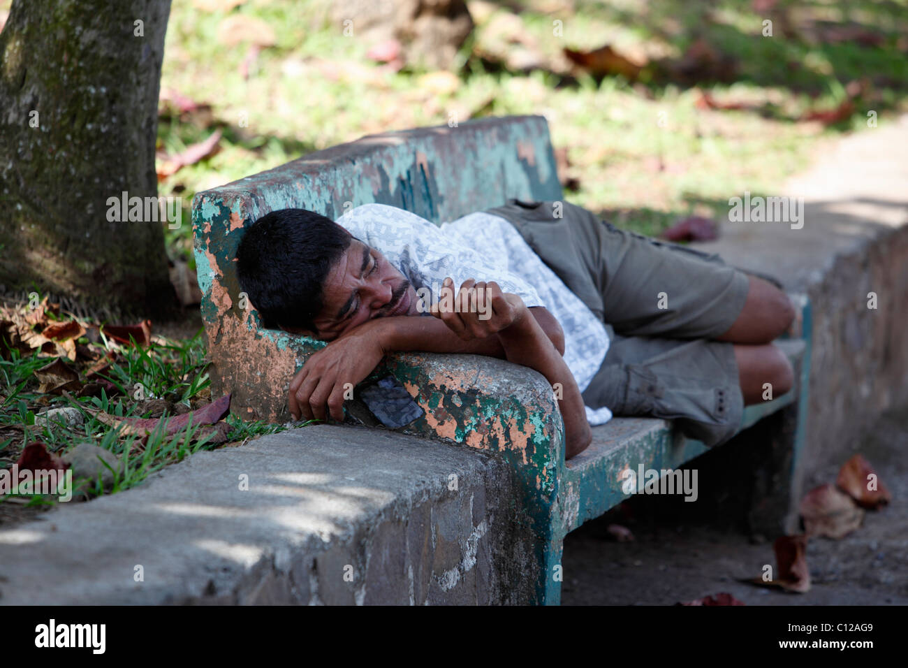 Un hombre Costarricense durmiendo en una banca del parque en Quepos, Costa Rica Foto de stock