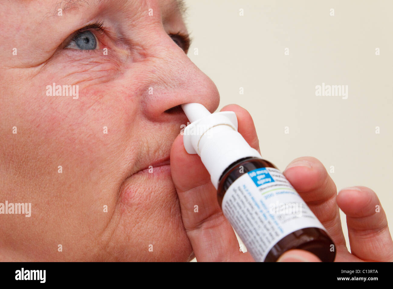 Mujer sufre de fiebre del heno squirting Beconase inhalador de alivio de la fiebre del heno hasta una fosa de su nariz para aliviar los síntomas de alergia Foto de stock