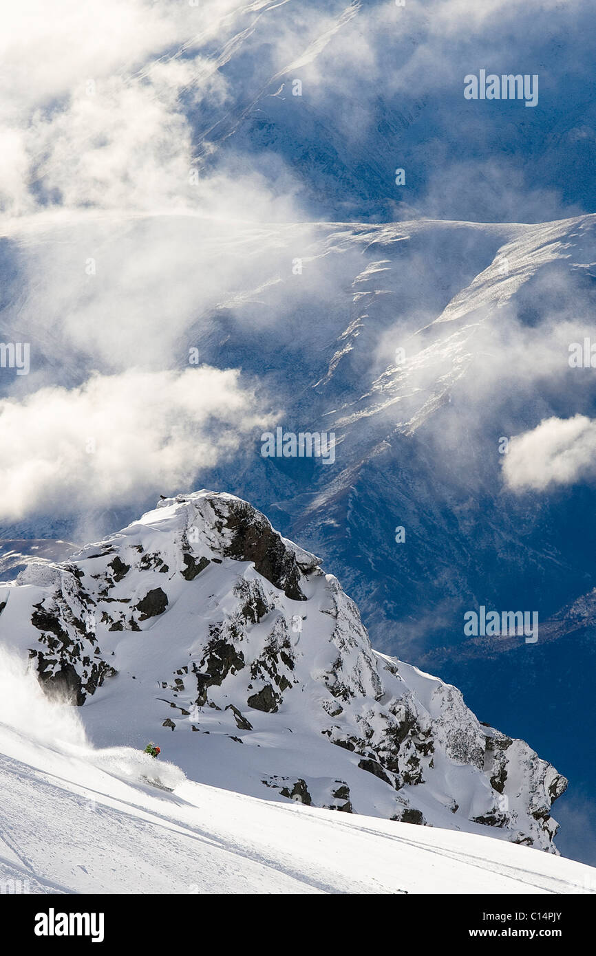 Un macho snowboarder rips un giro en una profunda capa de polvo mientras snowboard en una cordillera en Queenstown, Nueva Zelanda. Foto de stock