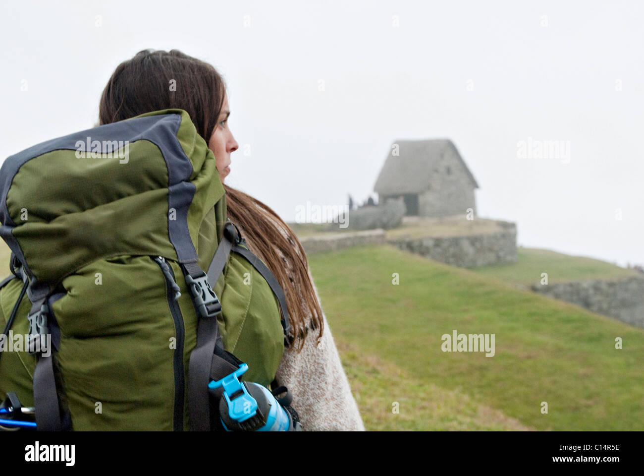 Una joven mujer caminatas hacia las ruinas de Machu Picchu en una niebla por la mañana. Foto de stock