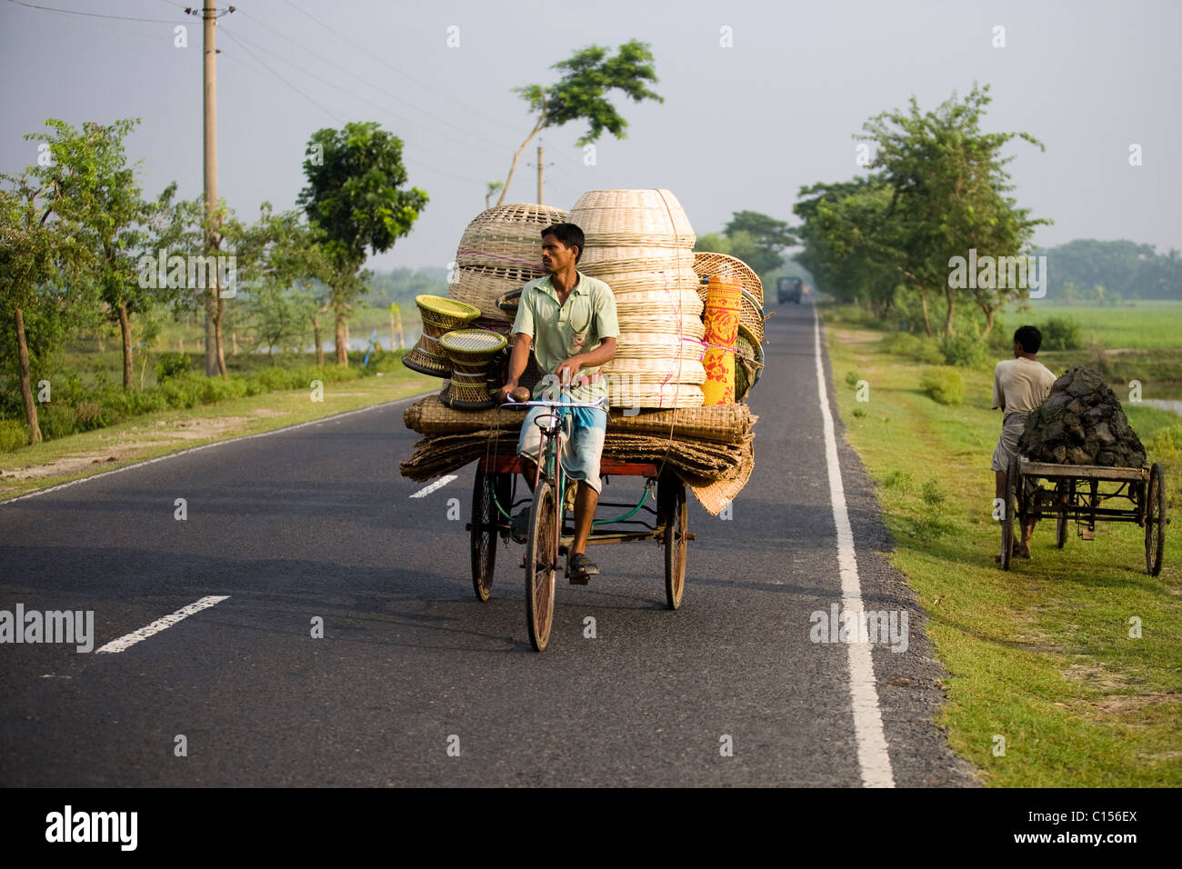 El hombre la venta de cestas de mimbre en el Bangladesh rural transporta mercancías en bicicleta Foto de stock