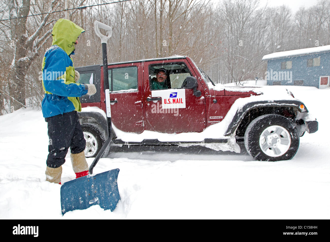 Hombre apalear la calzada nieve hablando con nosotros mailman, cartero, New Hampshire, Nueva Inglaterra, EE.UU. Foto de stock