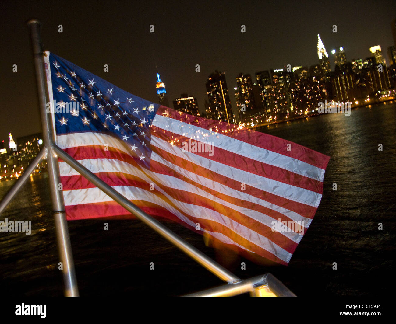 Bandera norteamericana delante de Manhattan por la noche Foto de stock