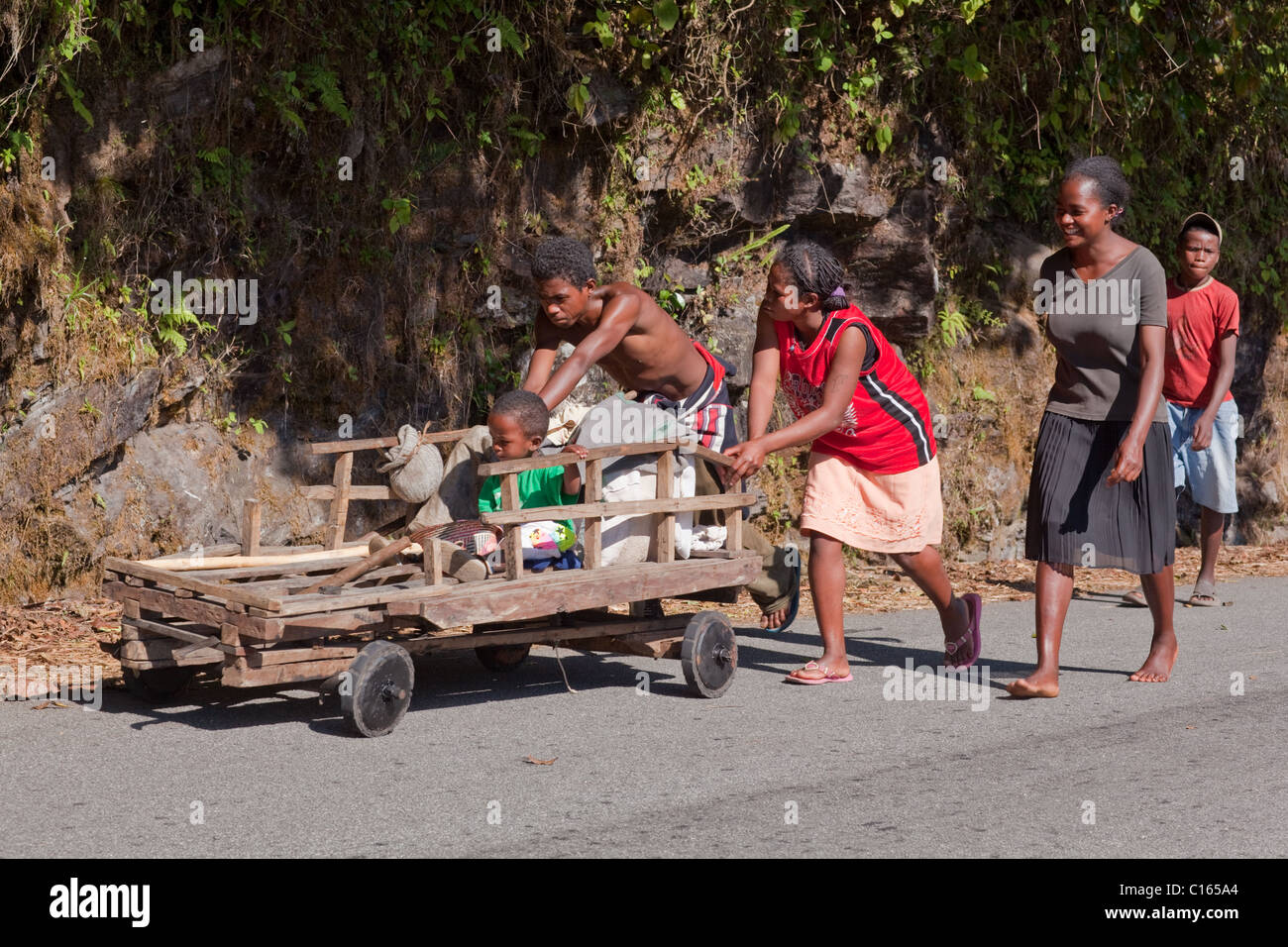 Familia empujando carrito de equipaje hasta una colina. Ranomafarna, Madagascar. Foto de stock