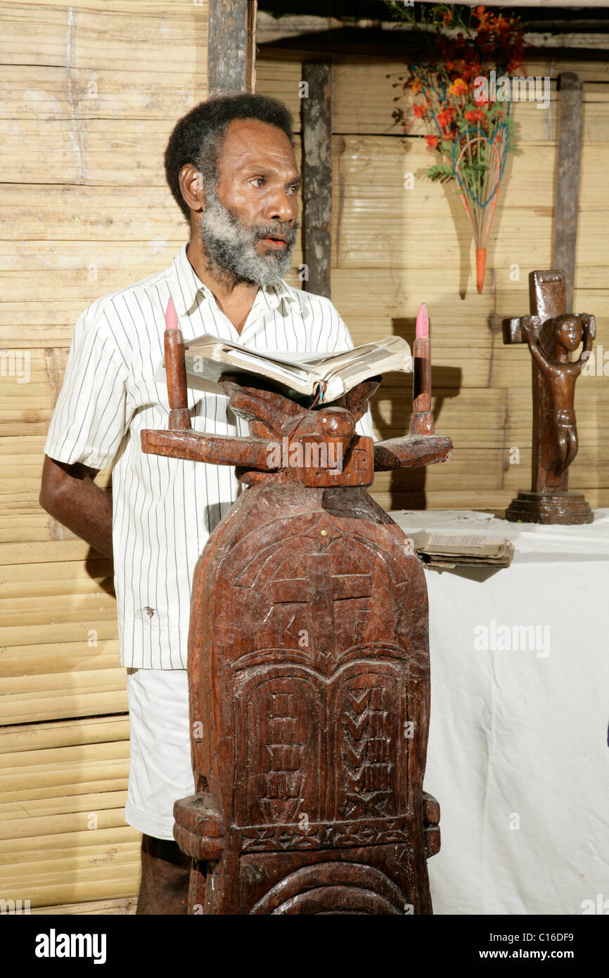 Hombre leyendo en el altar, servicios religiosos, Mindre, Papua Nueva Guinea, Melanesia Foto de stock