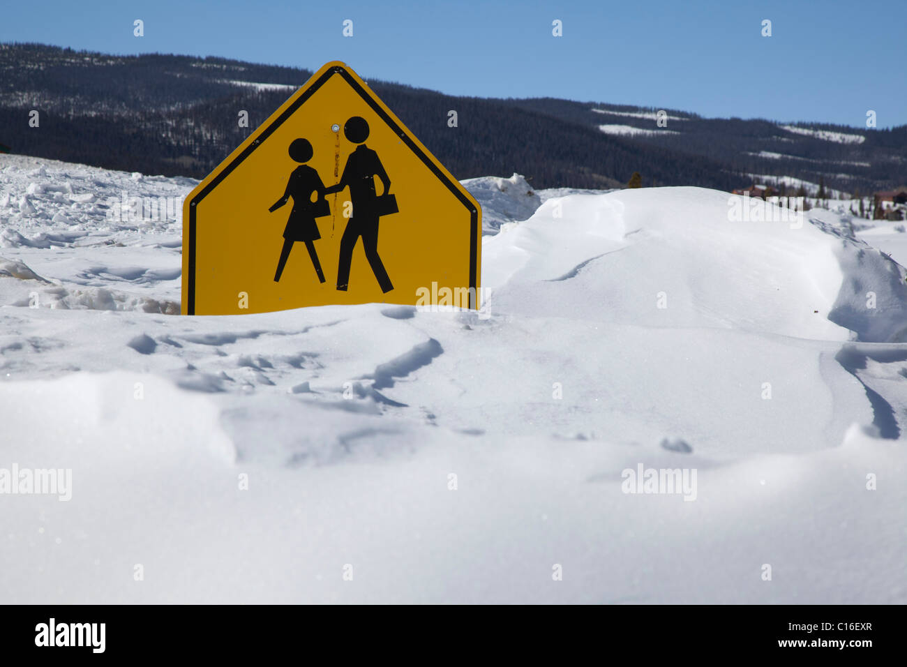 Granby, Colorado - Un signo de cruce escolar está casi enterrado por la profundidad de la nieve en las Montañas Rocosas. Foto de stock