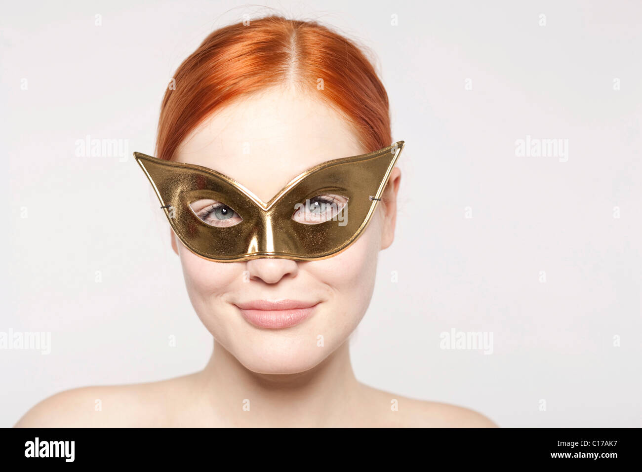 Joven pelirroja mujer vistiendo una máscara de oro Foto de stock