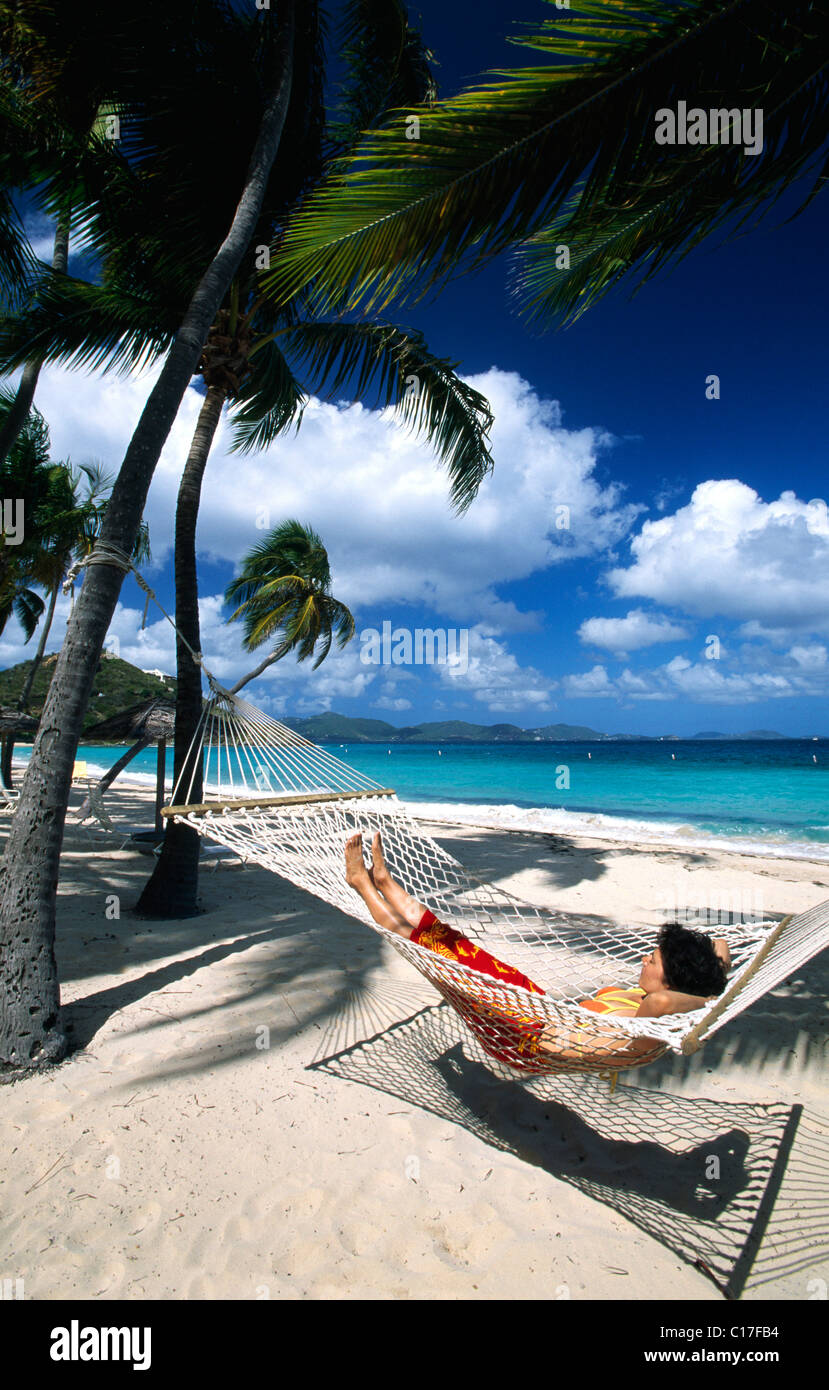 Mujer en una hamaca bajo palmeras en una playa en Peter Island, Islas  Vírgenes Británicas, el Caribe Fotografía de stock - Alamy