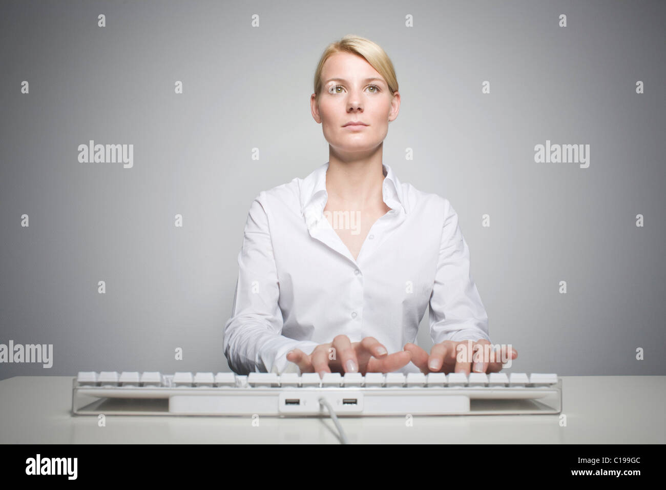 Joven Mujer rubia escribiendo en un teclado de ordenador. Foto de stock