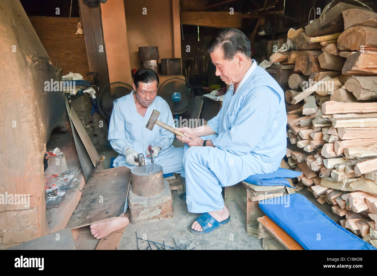 Artesanos haciendo picar palos de metal utilizando los métodos tradicionales, Corea Folk Village, Suwon, Corea del Sur Foto de stock