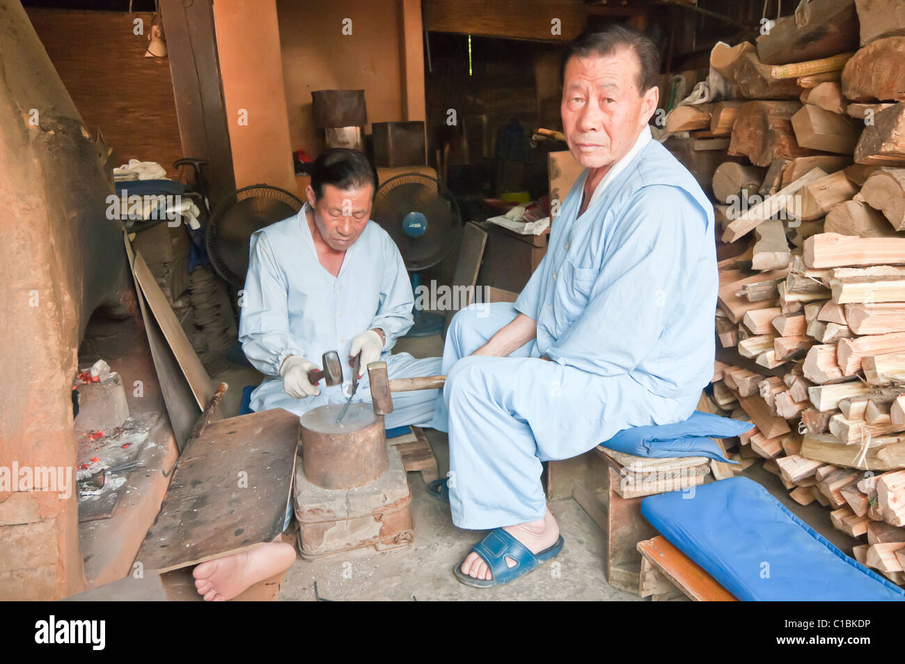 Artesanos haciendo picar palos de metal utilizando los métodos tradicionales, Corea Folk Village, Suwon, Corea del Sur Foto de stock