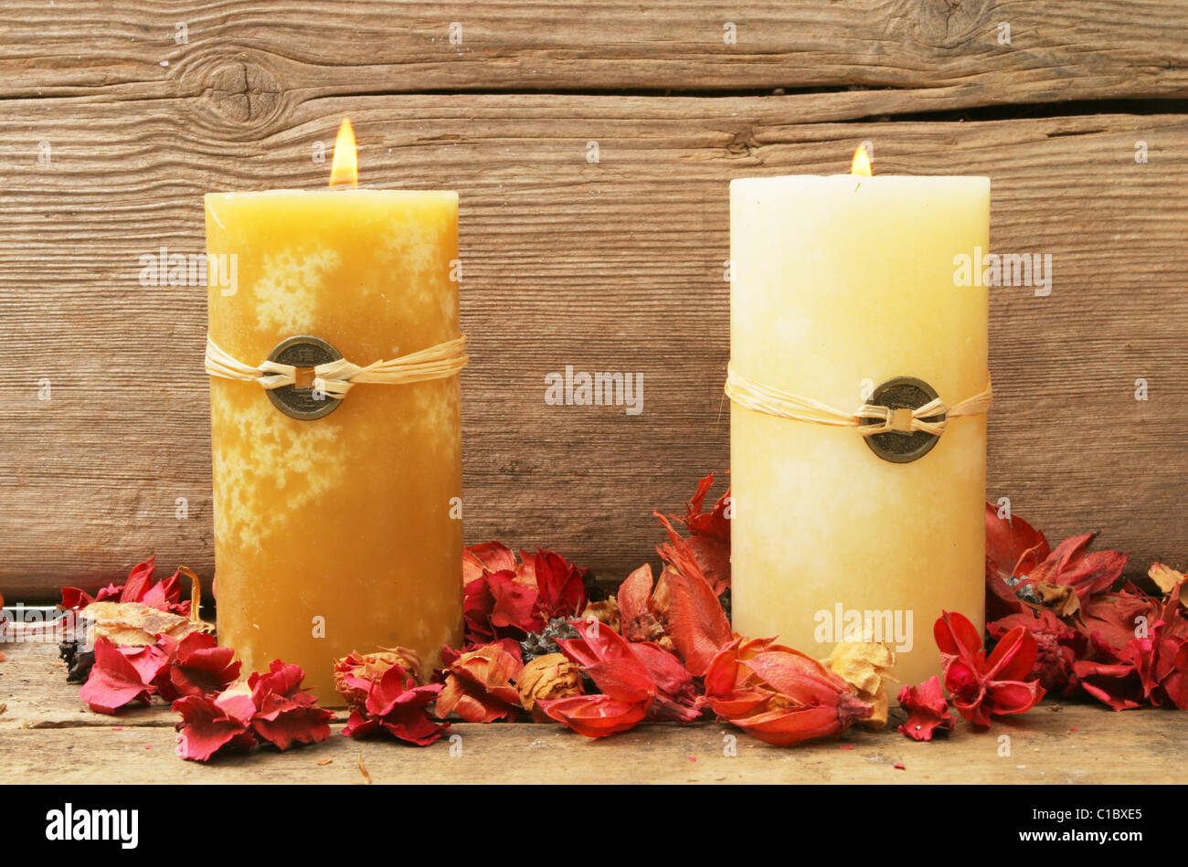 Dos quema feng shui velas con flores secas sobre un fondo de madera vieja Foto de stock