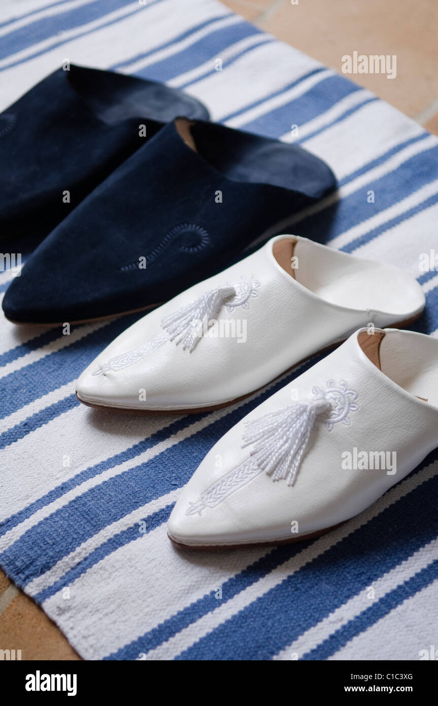 Dos pares de zapatillas marroquíes sobre una alfombra de rayas azul Foto de stock