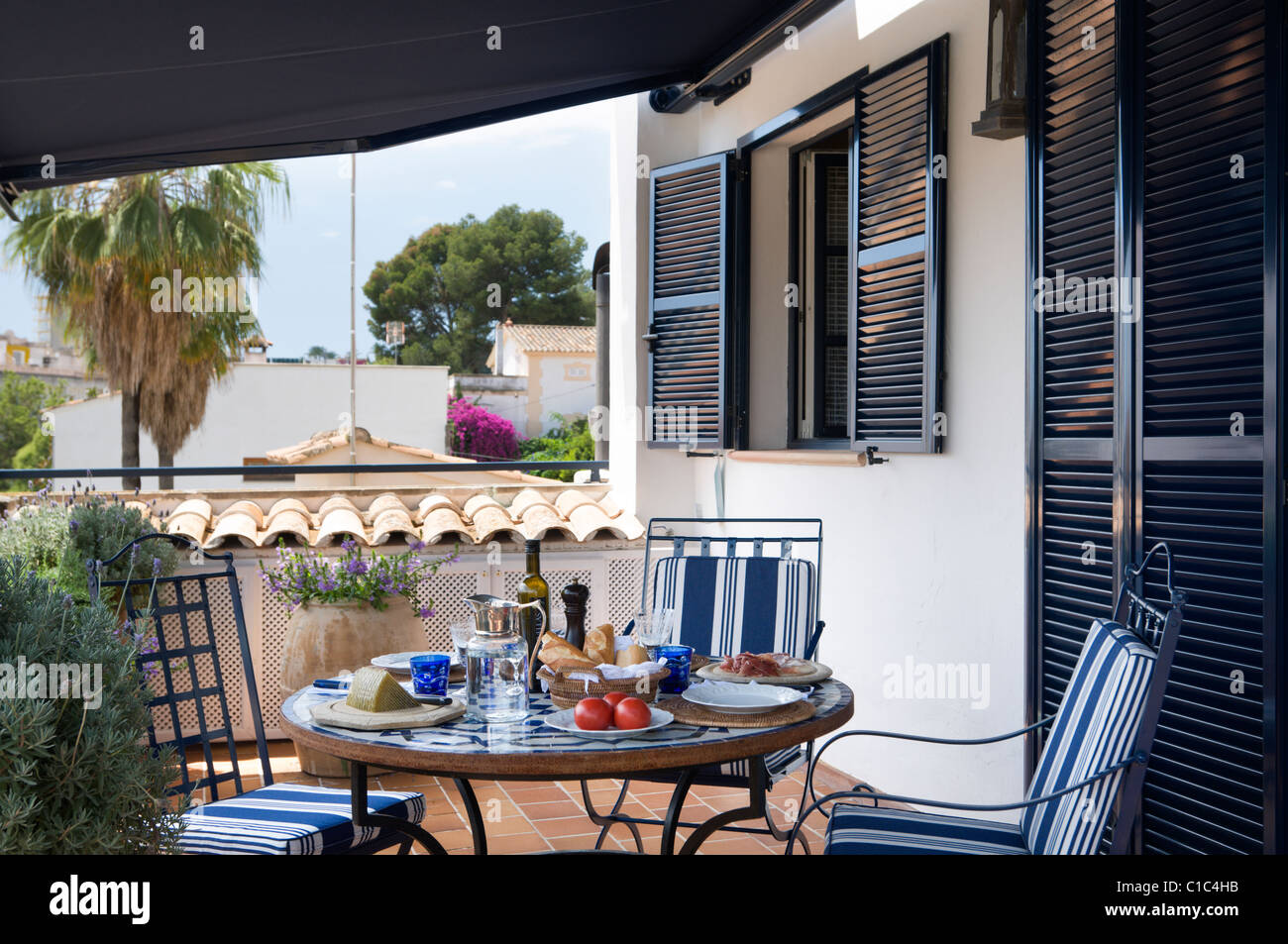 Conjunto almuerzo tabla en español veranda con cojines de tela a rayas azules sobre sillas Foto de stock